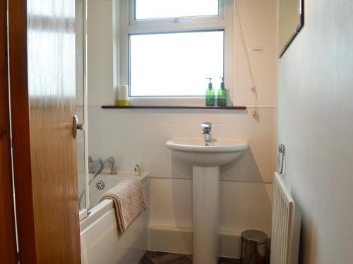 uma casa de banho com um lavatório e uma banheira em Iona Cottage em Clarencefield