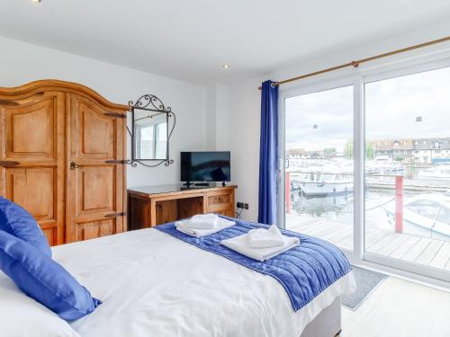 a bedroom with a bed and a large window at Jib Sail-18148 in Wroxham