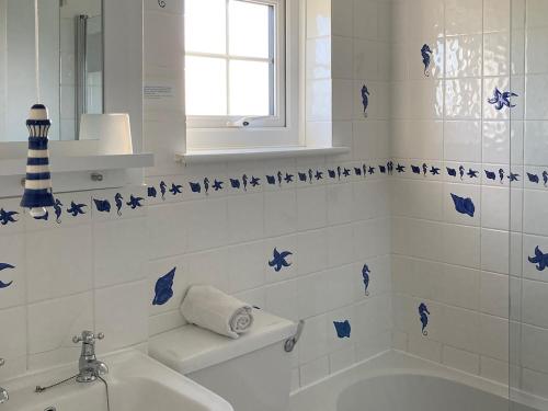uma casa de banho com uma banheira e um lavatório com borboletas azuis em 3 The Coastguards em Downderry