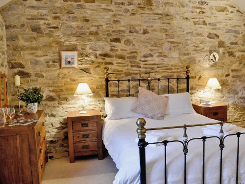 a bedroom with a bed and a stone wall at Penno Cottage - 24440 in Bodmin