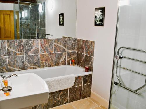 a bathroom with a bath tub and a sink at Penno Cottage - 24440 in Bodmin