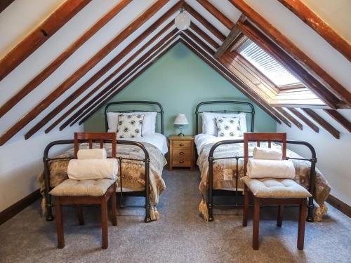 two twin beds in a attic bedroom with wooden beams at Horsepark Cottage in Girthon