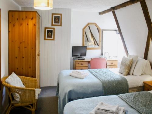 a room with two beds and a desk and a television at Churchview House in Winterborne Abbas