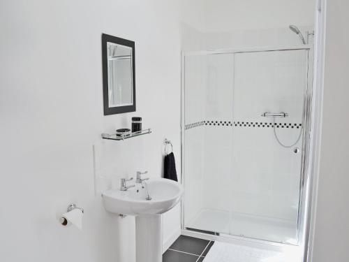 a white bathroom with a sink and a shower at Myrtle Cottage - 28177 in Fairgirth