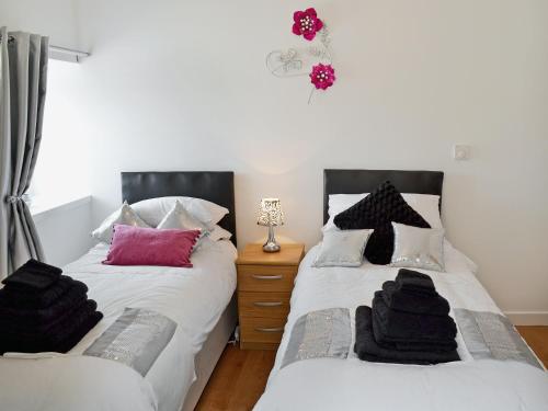 Duas camas num quarto a preto e branco em Myrtle Cottage - 28177 em Fairgirth