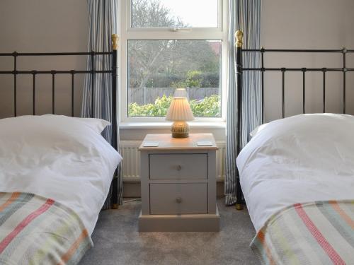 a bedroom with two beds and a lamp on a night stand at Little Cottage in Sheringham