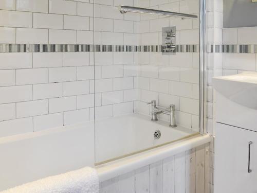 a white bathroom with a tub and a sink at Little Cottage in Sheringham