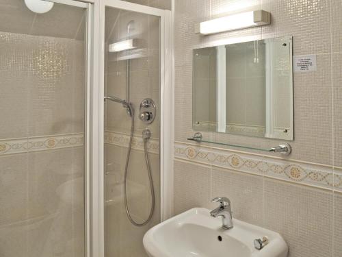 uma casa de banho com um chuveiro, um lavatório e um espelho. em The Limes em Swanwick