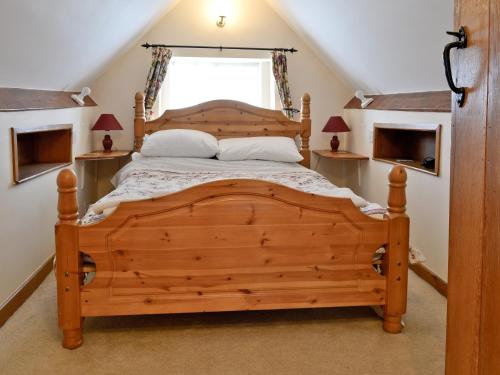 ein Schlafzimmer mit einem Holzbett im Dachgeschoss in der Unterkunft Gingerbread Cottage in Fairford