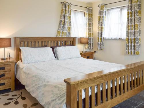 a bedroom with a large bed and two windows at Bryncrwn Cottage in Rhyd-y-felin