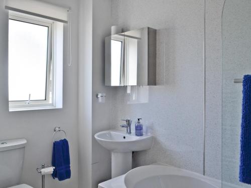 a white bathroom with a sink and a mirror at Rowanlea Cottage in Nairn