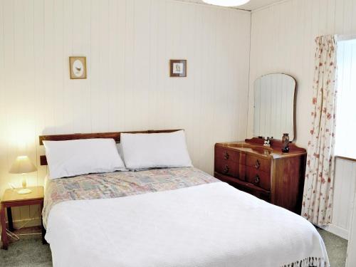 um quarto com uma cama, uma cómoda e um espelho em Glentairre Cottage - Swww em Balnaboth