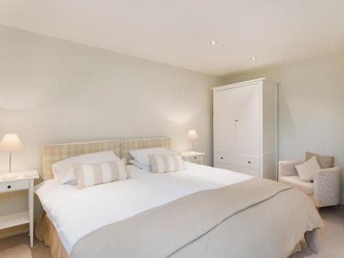 a bedroom with a large white bed and a chair at Hurworth - 25565 in Nether Silton