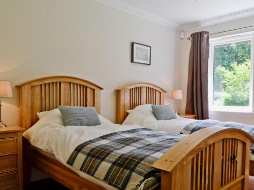 2 Einzelbetten in einem Schlafzimmer mit Fenster in der Unterkunft Oak Lodge in Saint Fillans