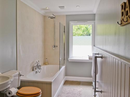ein Badezimmer mit einer Badewanne, einem WC und einem Waschbecken in der Unterkunft Oak Lodge in Saint Fillans