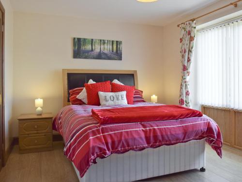 a bedroom with a bed with red pillows at The Smithy - Op6 in Carmarthen