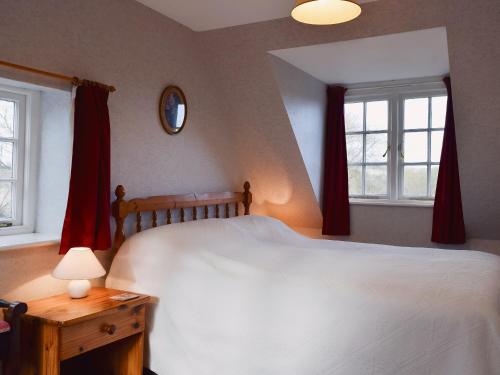 een slaapkamer met een wit bed en 2 ramen bij The Mill in Lindridge