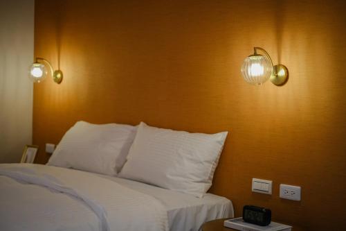 a bedroom with a bed and two lights on the wall at Giant Rich Hotel in Taipei