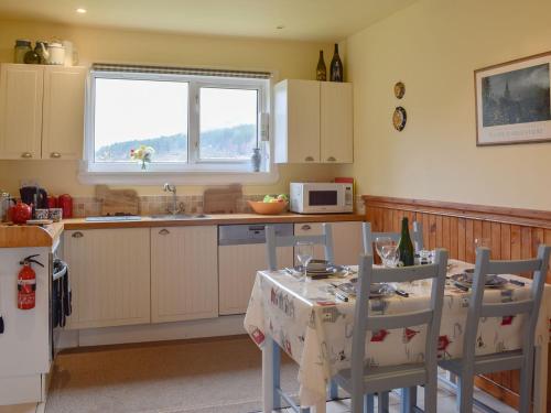 a kitchen with a table with two chairs and a microwave at Ardura Cottage in Lochdon