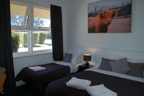 a bedroom with two beds and a bull on the wall at Calder Motel in Bendigo