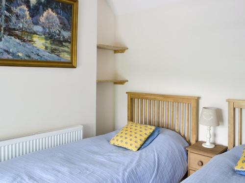 a bedroom with two beds and a painting on the wall at Dove Cottage in Great Rowsley