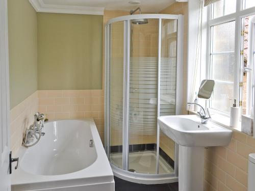 a bathroom with a bath tub and a sink at Dove Cottage in Great Rowsley