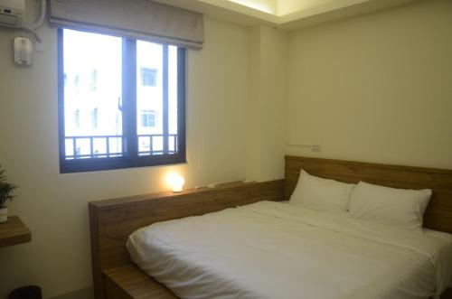 a bedroom with a white bed with a window at Rebecca Hostel in Chaozhou