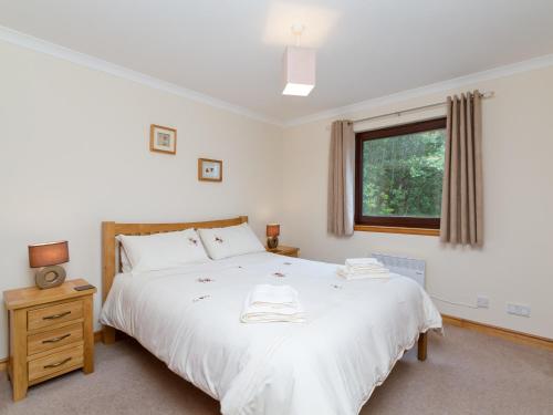 a bedroom with a large white bed and a window at Loch Duich Cottage in Inverinate