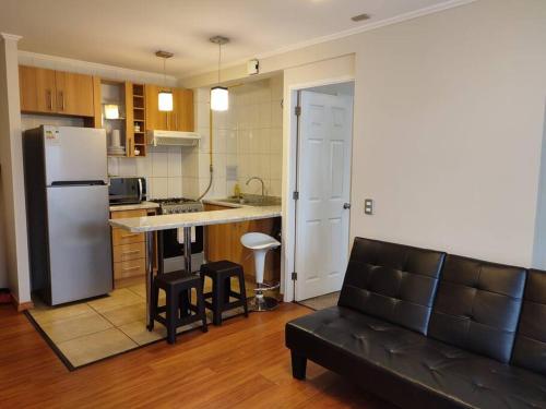 een woonkamer met een bank en een keuken met een koelkast bij Departamento amoblado muy cómodo in Puerto Montt