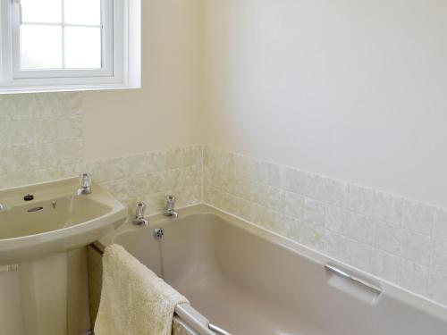 a bathroom with a bath tub and a sink at Dene Corner in Stokenham