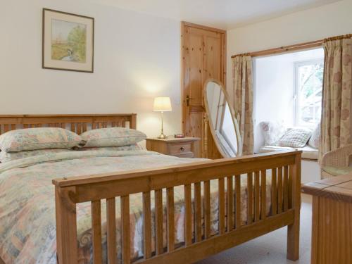 Schlafzimmer mit einem Holzbett und einem Spiegel in der Unterkunft Osprey Cottage in Dunkeld