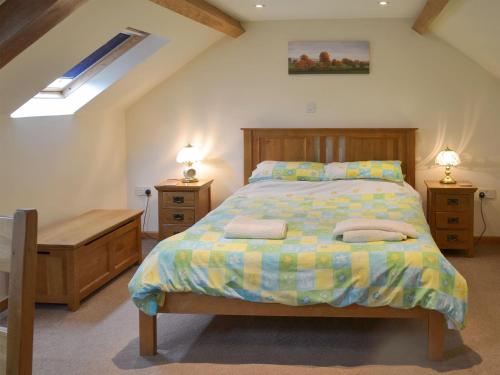 a bedroom with a bed and two night stands and two lamps at Clyst William Barn in Plymtree