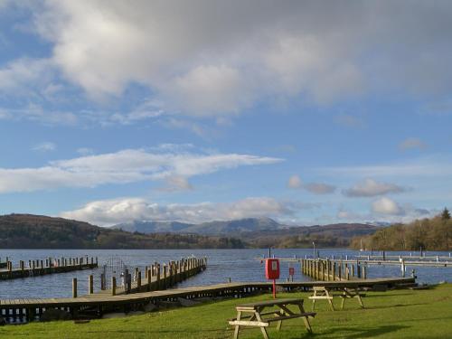 a lake with two picnic tables and a dock at Ashlea in Ravenglass