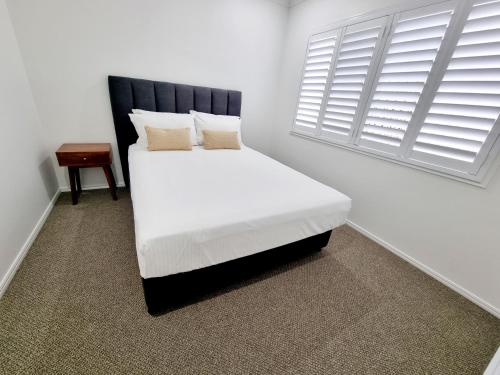 um quarto com uma cama branca e uma janela em Large and Private Executive Home - Secure parking for boats em Hervey Bay