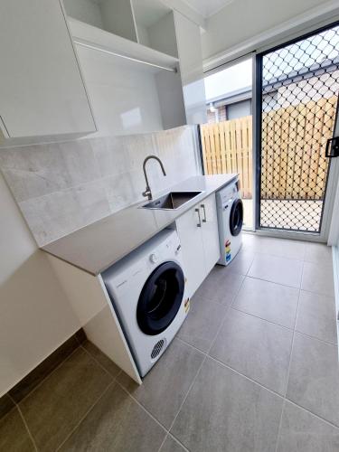 a kitchen with a washing machine and a sink at Large and Private Executive Home - Secure parking for boats in Hervey Bay