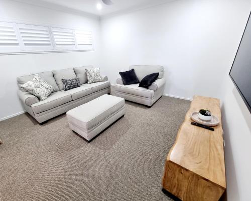 a living room with two couches and a coffee table at Large and Private Executive Home - Secure parking for boats in Hervey Bay