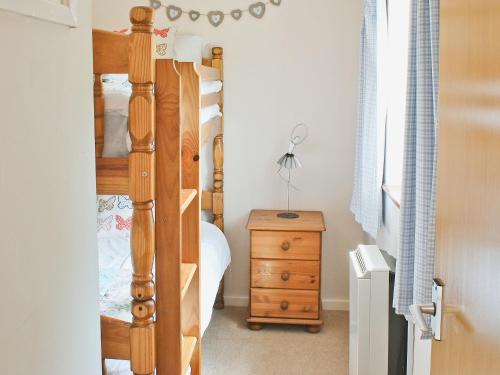 1 dormitorio con litera de madera y tocador de madera en Y Bwthyn, en Llangristiolus