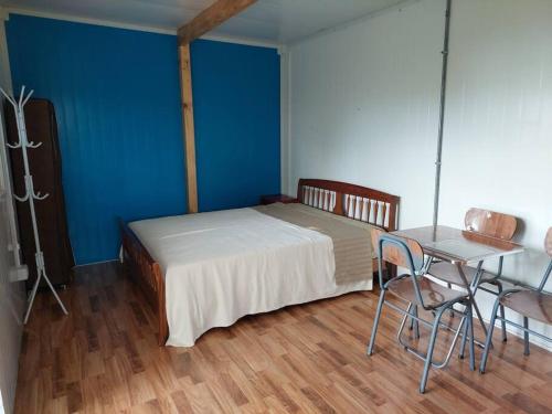 a bedroom with a bed and a table and a blue wall at Cabaña a orilla de playa, Pargua in Pargua