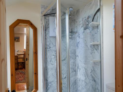 een douche in een badkamer met een marmeren muur bij Railway Cottage in Wool
