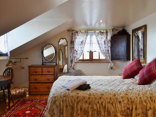 een slaapkamer met een bed, een dressoir en een spiegel bij Railway Cottage in Wool