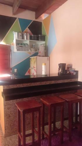 a bar with three stools and a counter with a counter top at Pousada Recanto do Galo in Santa Cruz Cabrália