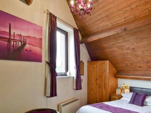 um quarto com uma cama e um tecto de madeira em The Stable Loft em Bowness-on-Windermere