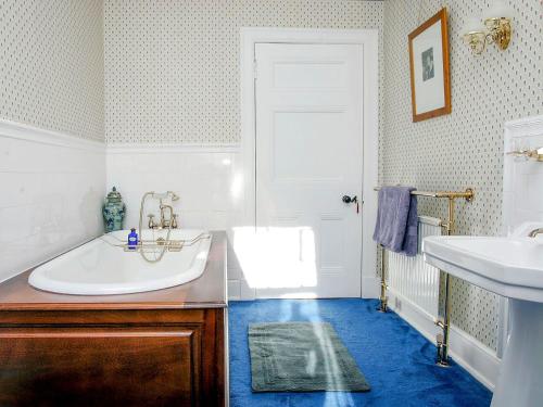 a bathroom with a white tub and a sink at Dunvarlich House in Aberfeldy