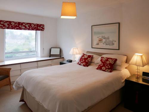 a bedroom with a large white bed with red pillows at Topsail in Newton Ferrers