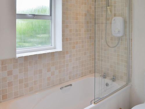 a bathroom with a bath tub and a window at Topsail in Newton Ferrers