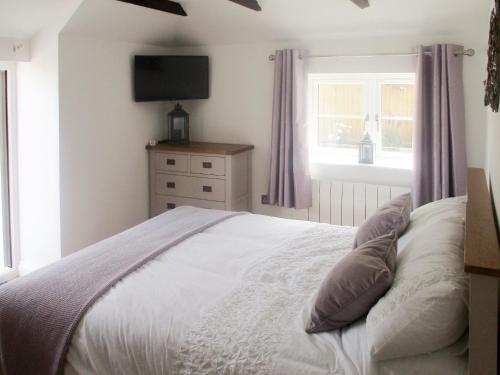 a bedroom with a bed with a television on the wall at Bluebell Cottage in Nether Stowey
