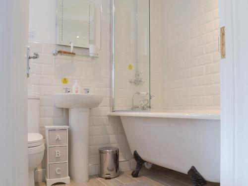 a bathroom with a tub and a sink and a toilet at Bluebell Cottage in Nether Stowey