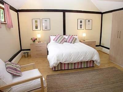 a bedroom with a large white bed and two tables at The Byre in Ninfield