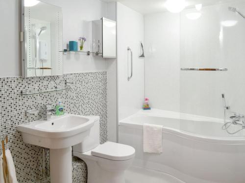 a white bathroom with a sink and a toilet and a tub at Cherry Tree Cottage in Bovey Tracey