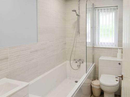 een witte badkamer met een bad en een toilet bij Bluebell in Saint Ewe
